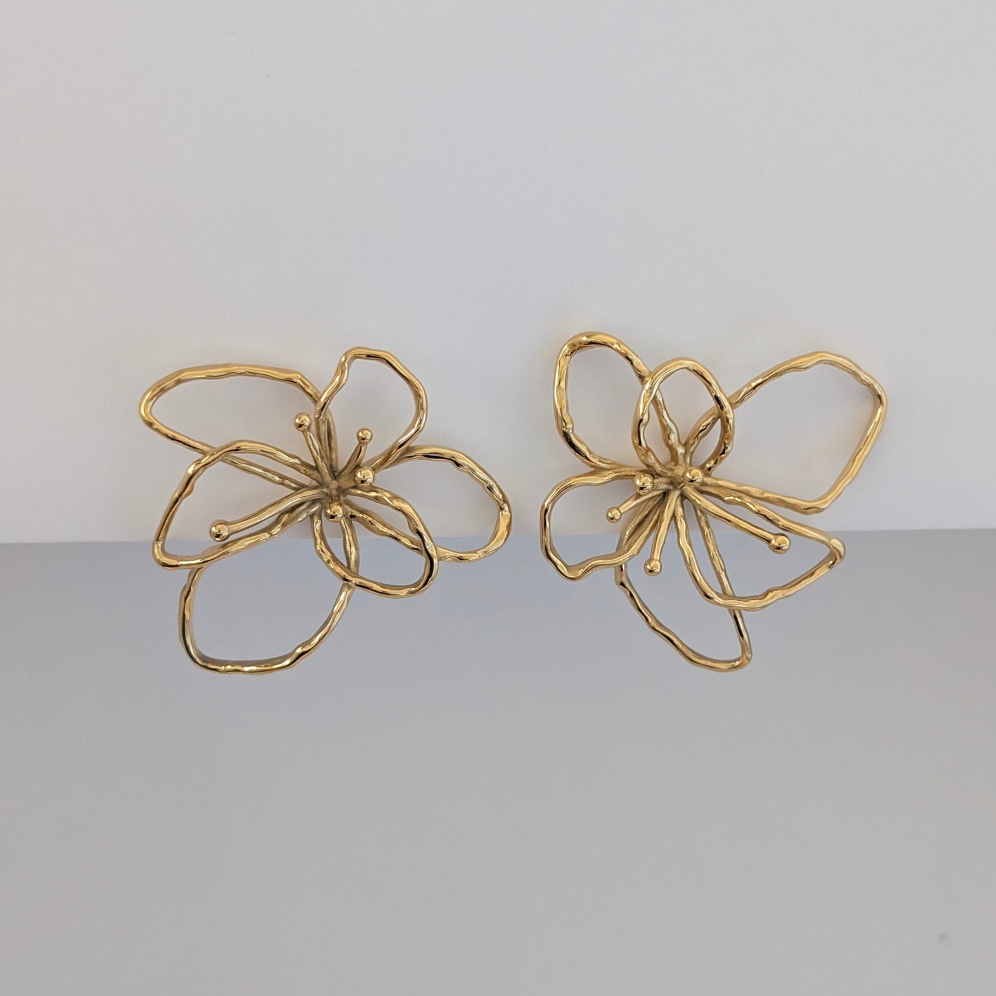 Front view of gold orchid statement earrings—18k plated, 4 × 4.21 cm sculptural floral studs.