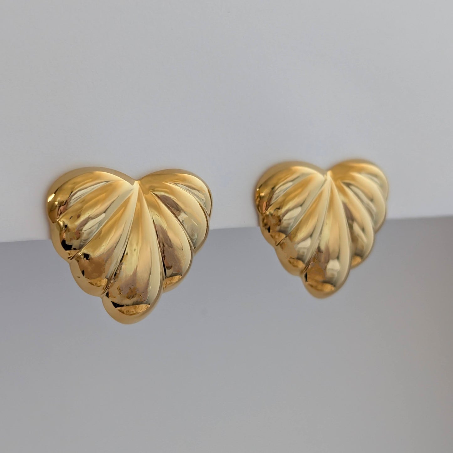 Side angle showing sculpted palm leaves and 2.6 × 3 cm size on gold statement earrings.