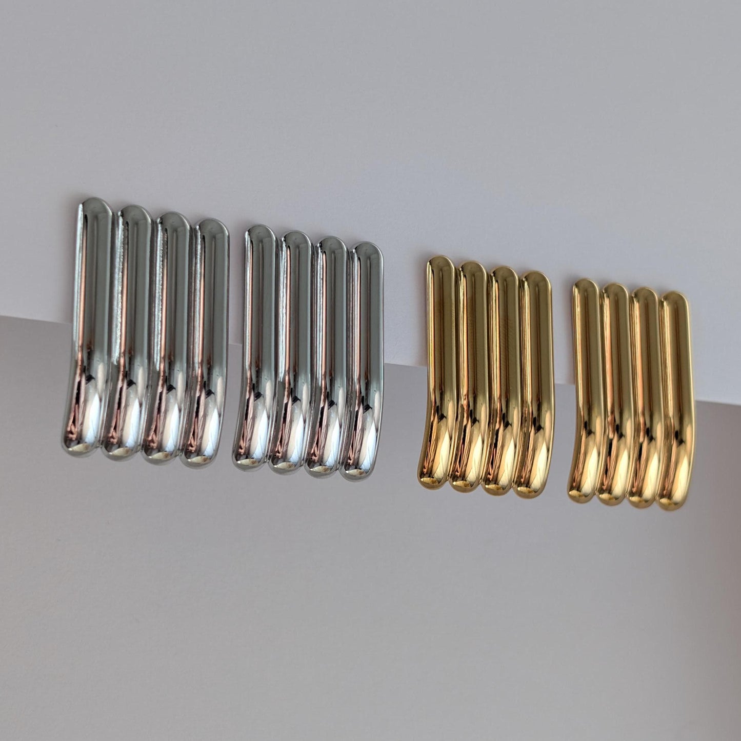 Side view of gold and silver sculptural stud earrings showing curved profile, 3.8 cm drop and hypoallergenic posts.