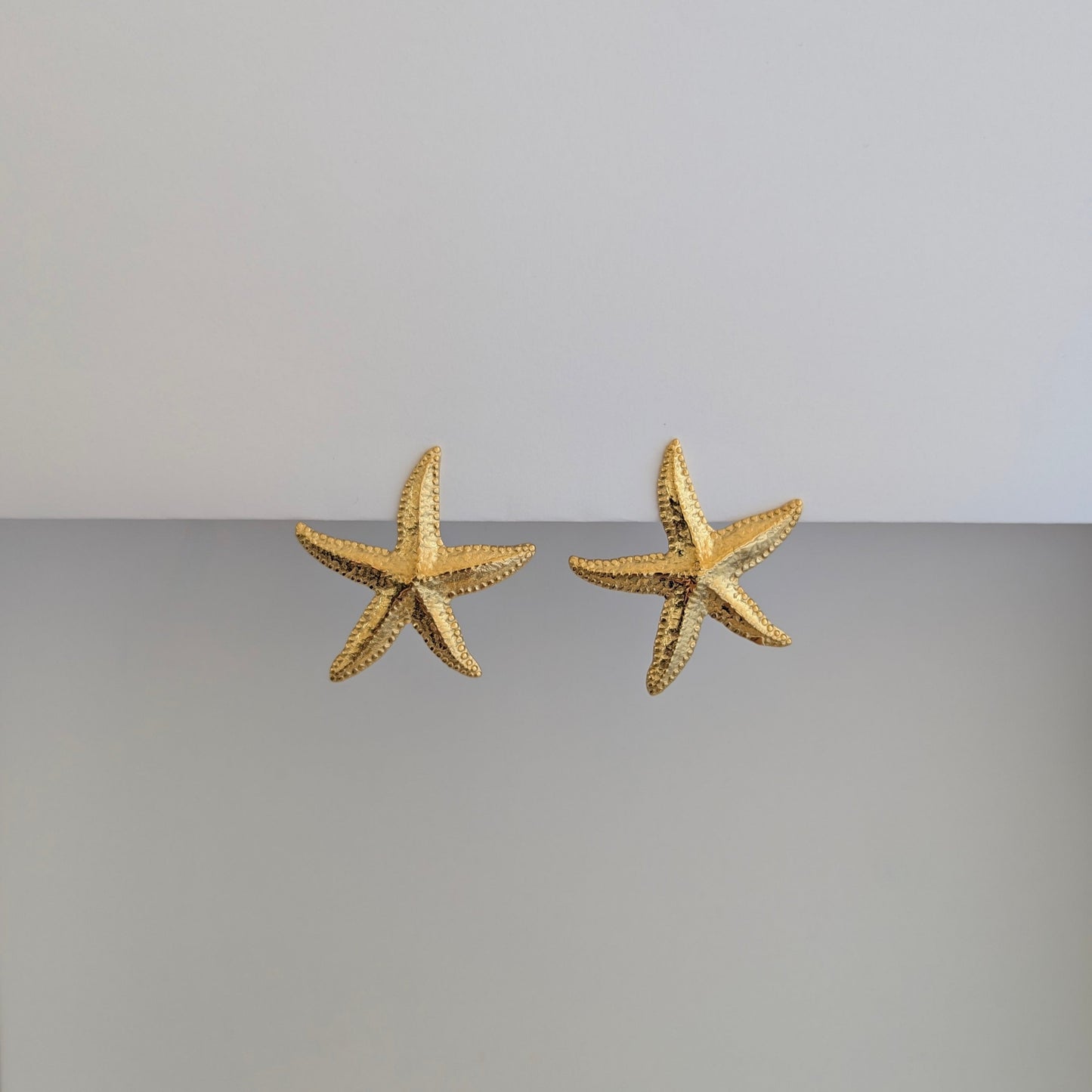 Alternate front angle of gold starfish stud earrings—18k gold plated, polished finish, sculpted texture.