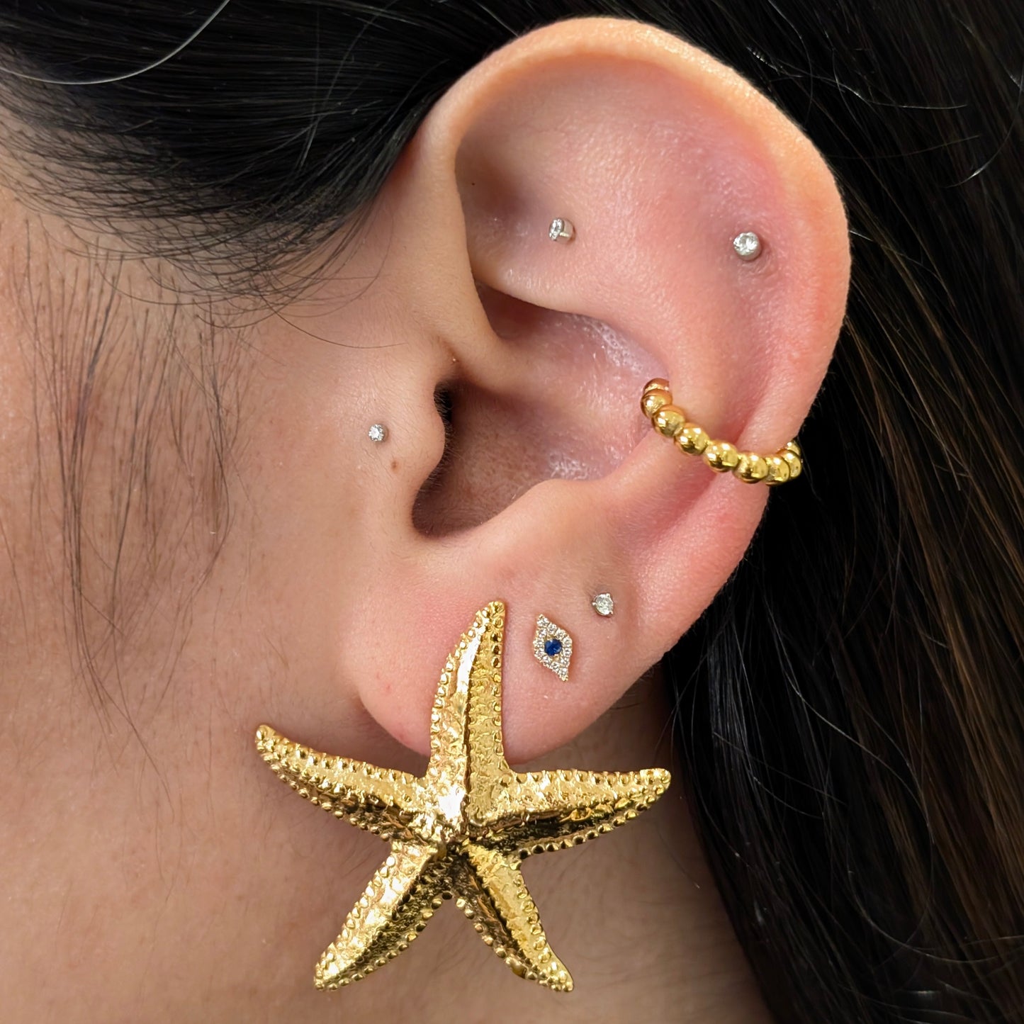 Lifestyle shot: Étoile gold starfish studs worn, beach‑ready statement style.