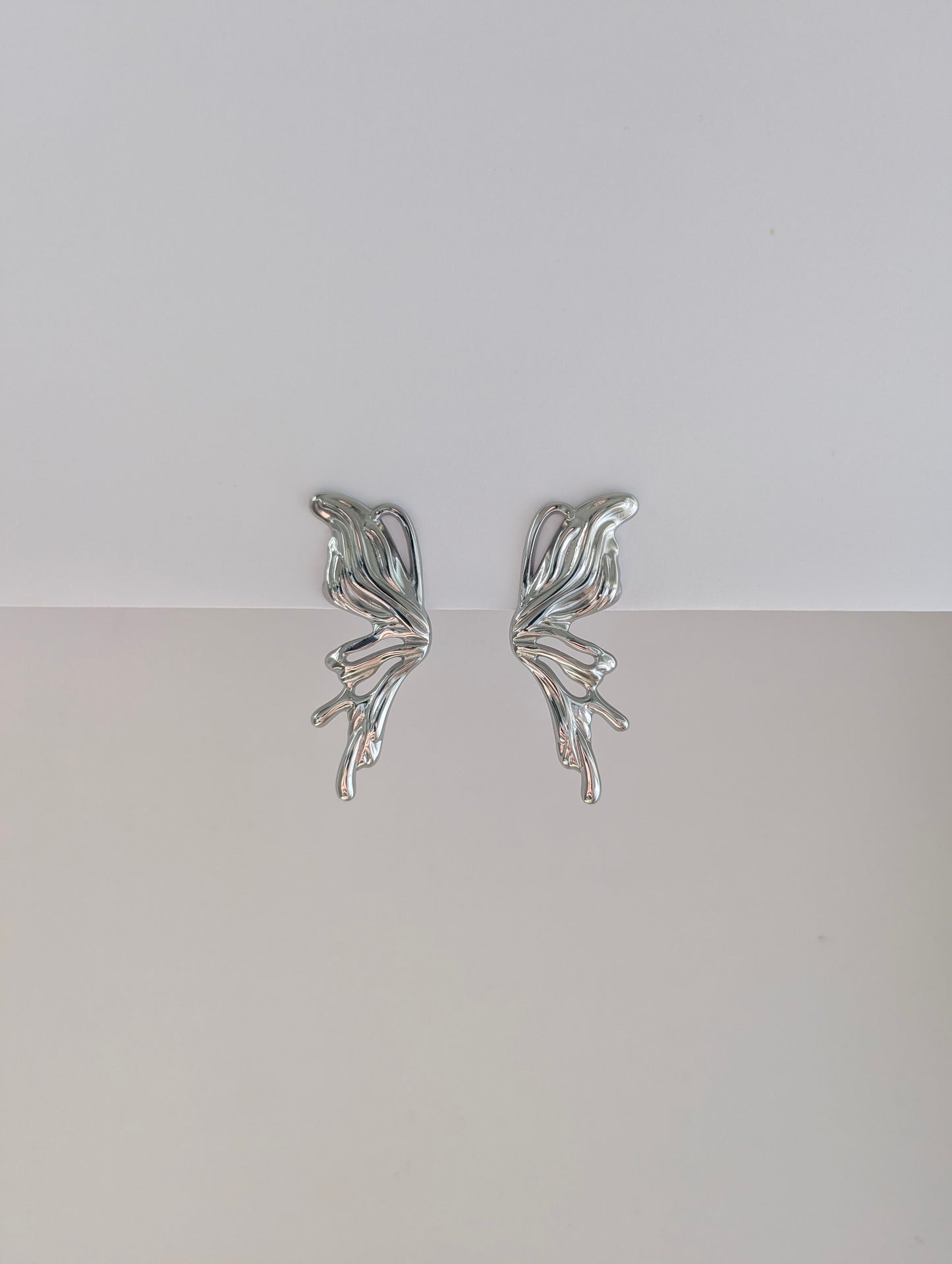 Front view of silver sculptural statement earrings—polished stainless steel, 4.6 × 2.1 cm droplet design.