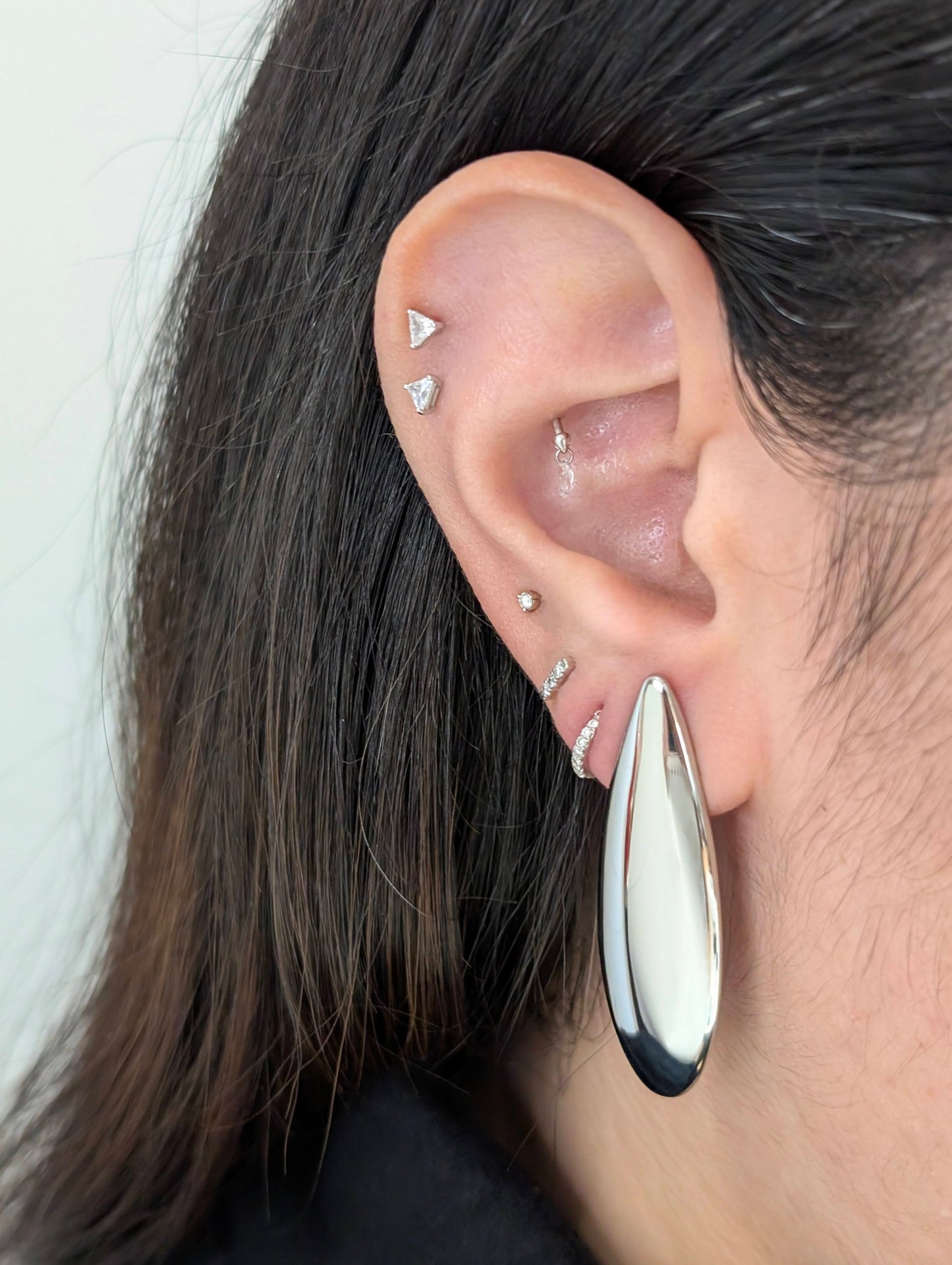 Second on‑ear view of Raya silver teardrop statement earrings, highlighting polished shine and elegant 4.53 cm drop.