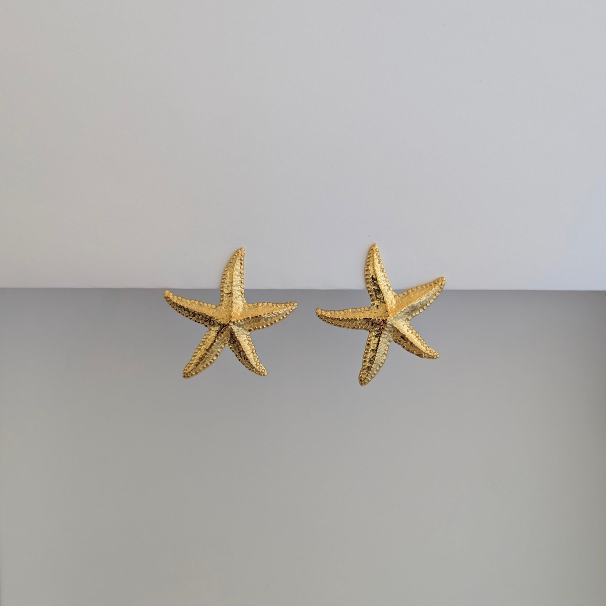 Alternate front angle of gold starfish stud earrings—18k gold plated, polished finish, sculpted texture.